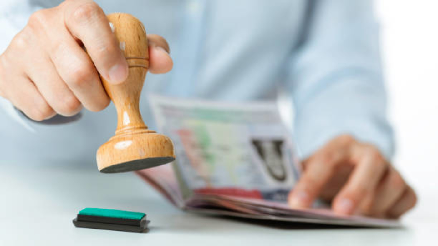 Unrecognizable person is about to stamp on passport where a visa is visible.